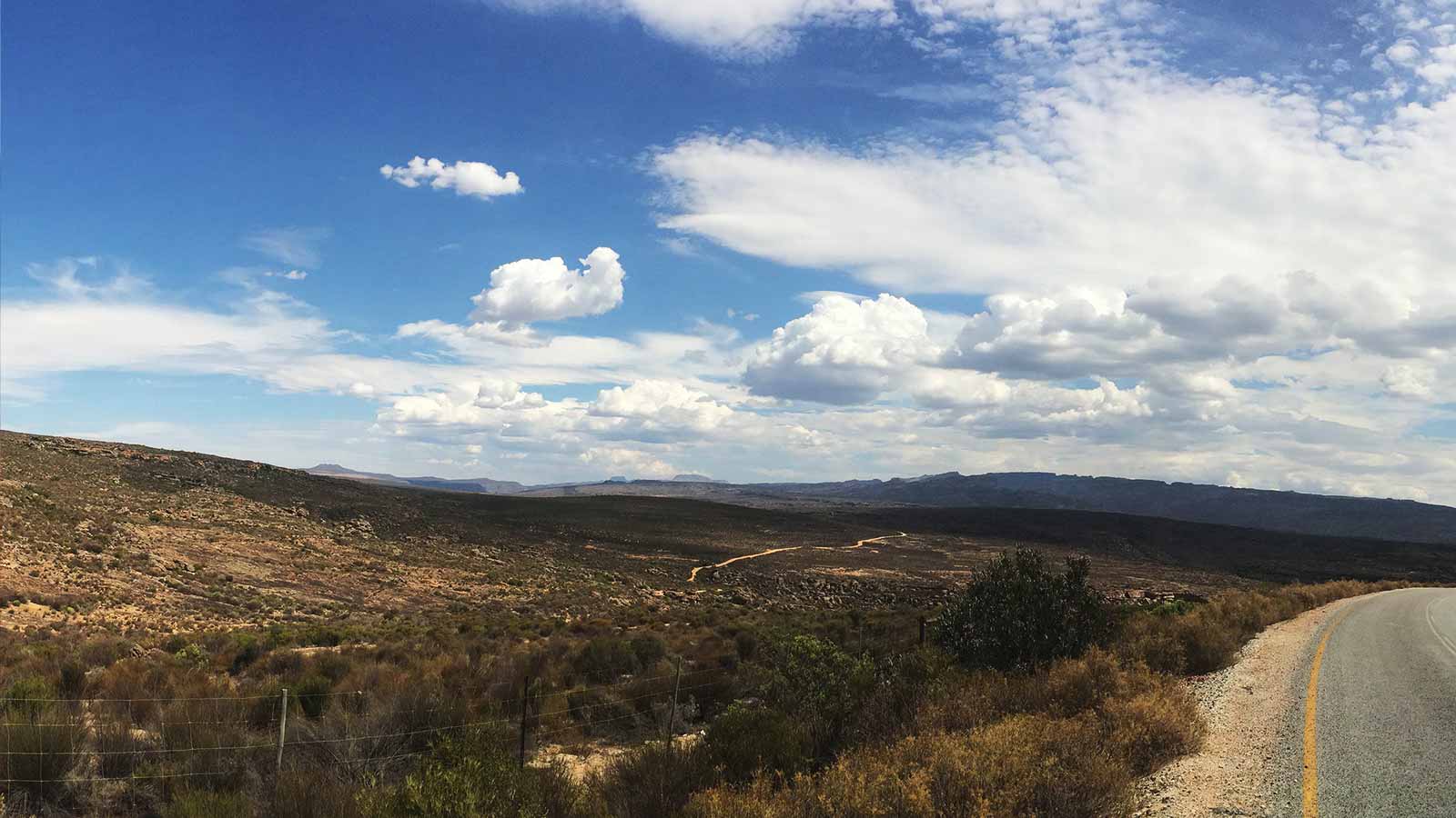 Cederberg desert landscape with a road and blue sky with clouds.